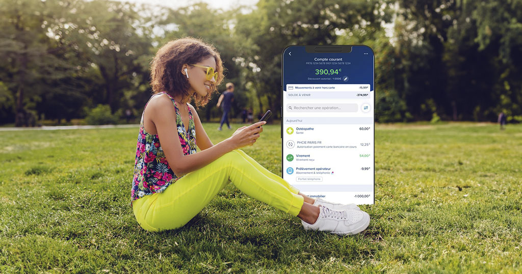 Une personne assise dans un parc consulte son téléphone