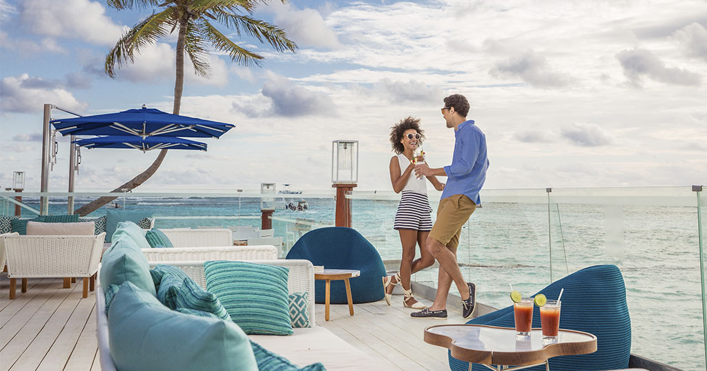 Un couple se détend avec des boissons sur une terrasse en bord de mer