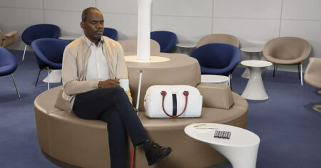 Aveugle assis avec sa canne, un café et un sac Air France